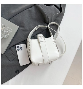 Détails d'un sac seau blanc avec rivets argentés et fermeture à boucle métallique