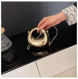 Dettaglio ravvicinato di una borsa da sera rotonda color oro con catena in metallo