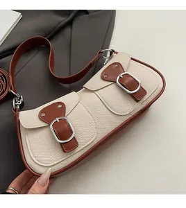 Detail der beigefarbenen Canvas-Baguette-Tasche mit braunen Ledertaschen und Schnallen