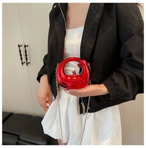 Detail of red metallic mini bag with circular hollow design and golden chain strap