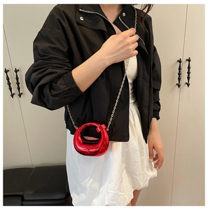 Close-up of a red metallic round mini crossbody bag with a gold chain strap and ring handle