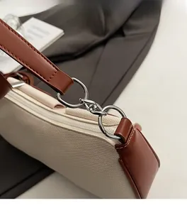 Detail der silbernen Metallbeschläge an beiger Canvas-Baguette-Tasche mit braunem Leder