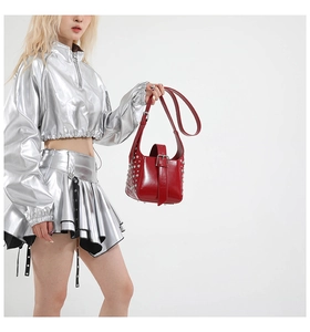 Gros plan du sac à main en cuir verni rouge avec rivets argentés et boucles métalliques
