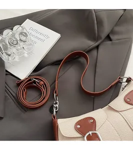Detail der cremeweißen Baguette-Tasche aus Strukturstoff mit braunem Leder und Silberschnalle