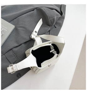 Détails de la bandoulière large réglable et des rivets argentés sur ce sac blanc chic