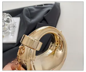 Detail of a metallic gold handbag showing the chunky circular handle and fine chain strap