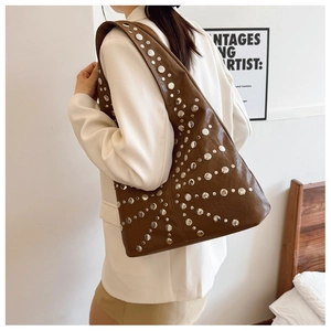 Nahaufnahme braune Vintage-Ledertasche mit Nieten auf einem weißen Sakko getragen