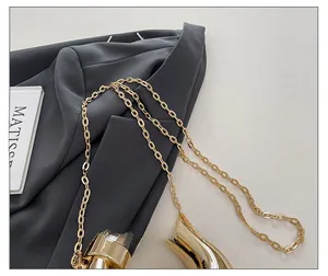Close-up of polished gold chain strap on acrylic bag with sleek metallic finish