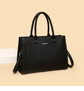 Detail of black leather tote showing woven texture and silver FASHION & BAGS logo