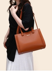 Detail of caramel brown pebble leather tote bag with stylish braided side accents