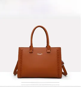 Macro detail of brown litchi pattern leather tote with woven strips and logo