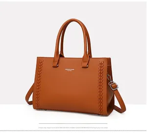 Detail of brown litchi pattern leather tote with woven side texture and twin handles
