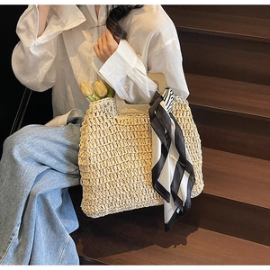 Beige straw tote bag with wooden handles and striped scarf for summer beach vacation