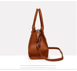 Detail view of brown lychee leather tote bag showing side accordion fold and silver hardware