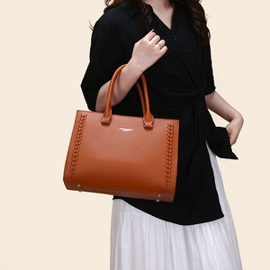 Detailed view of brown lychee-textured leather tote bag with unique woven side stitching