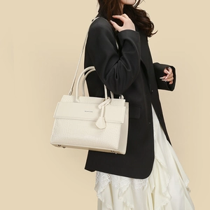 Close-up of cream faux crocodile texture handbag with adjustable shoulder strap