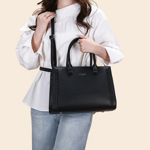 Detailed view of black pebble leather tote with side weaving and gold lettering