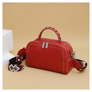 Detail of red boston bag with silver studs and geometric woven wide shoulder strap
