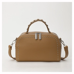 Close-up of khaki pebbled leather handbag featuring silver studs and chain handle detail