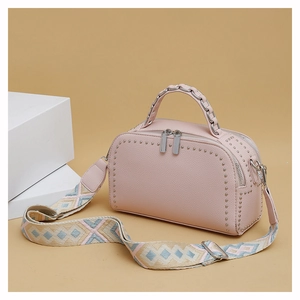Detail of pink lychee leather handbag with silver studs and embroidered strap