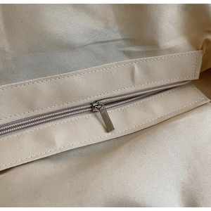 Macro shot of durable silver metal zipper on premium off-white canvas tote bag