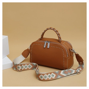 Detail of brown litchi pattern bag with silver studs and ethnic woven shoulder strap