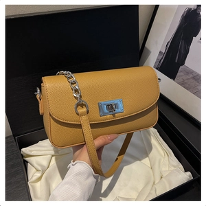 Detail of ginger yellow pebble leather bag with silver twist lock on white satin lining