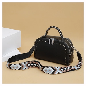 Close-up of black lychee leather bag with silver studs and embroidered strap