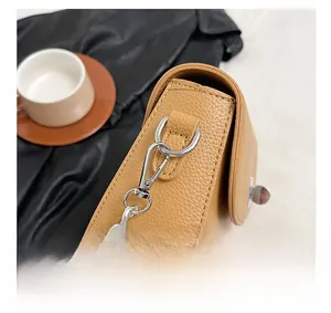 Detail showing high-quality lychee texture leather and silver hardware on ginger crossbody bag