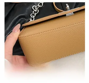 Macro detail of brown lychee grain leather stitching and silver metal chain strap