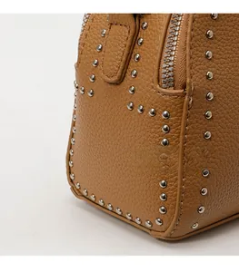 Detail shot of brown lychee grain leather with silver metal rivets and side zipper