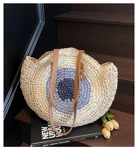 Detail of woven straw tote bag featuring blue concentric circles on wooden stairs