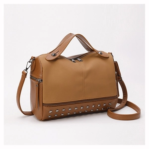 Close-up of brown patchwork PU leather bag featuring silver metal rivet studs on the bottom