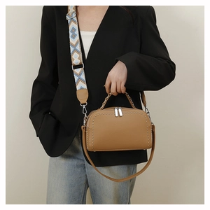 Model showing camel leather handbag with silver studs and geometric patterned wide strap