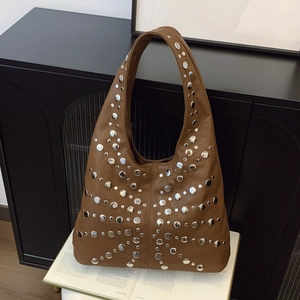 Brown leather Hobo bag with silver studs on an open book, vintage aesthetic style