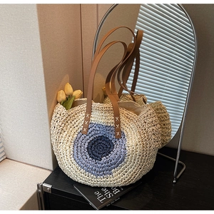 Detail of hand-woven straw tote with leather handles and blue evil eye design