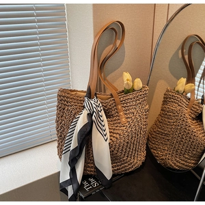 Woven straw tote bag with leather straps and decorative silk scarf for beach vacations