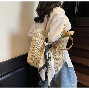 Large woven straw tote bag with brown leather straps and decorative silk scarf for summer