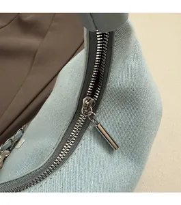 Close-up of the smooth silver zipper and denim texture on the light blue cloud bag