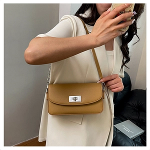 Close-up of ginger yellow crossbody bag with lychee texture and silver twist lock
