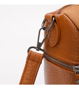 Detailed macro view of dark brown pebbled PU leather bag with premium charcoal hardware hooks