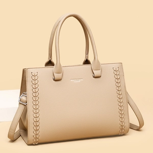 Beige faux leather tote bag with braided stitching and adjustable strap in studio setting