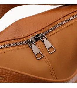Detail shot of gunmetal dual zippers on brown lychee pattern leather handbag