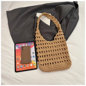 Detailed knit texture of a beige crochet shoulder bag with openwork pattern on white fabric