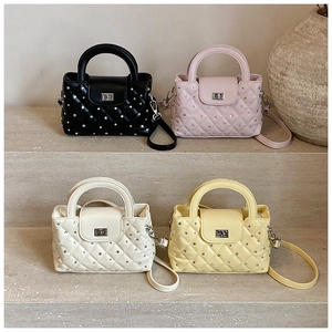 Close-up of four quilted rhinestone handbags in black pink white and yellow displayed on steps