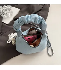 Macro shot of light blue denim handbag interior showing large capacity and chain strap