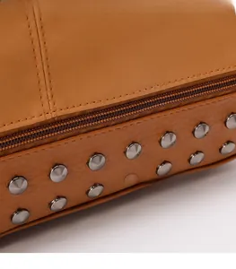 Macro view of brown PU leather bag featuring a zipper closure and metallic rivet details