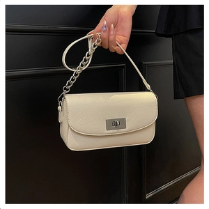 Close-up of beige lychee textured handbag with silver chain and metal turn-lock