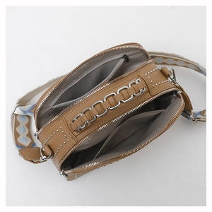 Detail view of brown crossbody bag featuring multi-compartment interior and wide woven strap