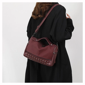 Detail of burgundy PU leather handbag featuring silver rivet studs and adjustable strap